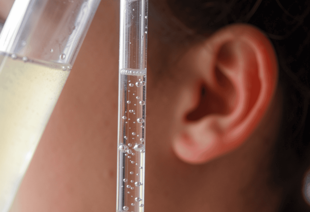 Person listenig to bubbles in a glass test tube